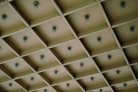 A modern geometric ceiling design featuring a grid pattern with light bulbs for architectural aesthetics.